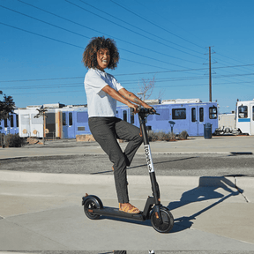 A girl enjoys a leisurely ride on the Hoverfly GXL MAX Electric Scooter amidst picturesque scenery, showcasing its foldable design for easy portability and a perfect companion for outdoor adventures